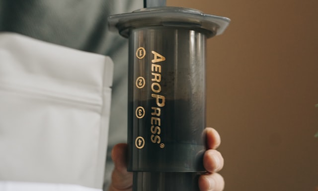 A hand holding an AeroPress coffee maker